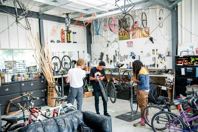 three students work inside the green bike program building